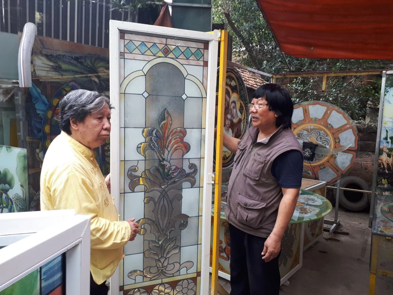 Ông Phạm Hồng Vinh (bên phải) đang giới thiệu nghệ thuật làm tranh kính.