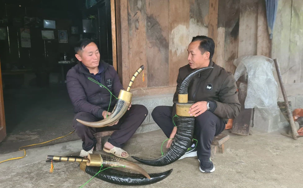 Ông Tẩn A Tung (trái ảnh) giới thiệu dao sừng trâu với khách hàng.