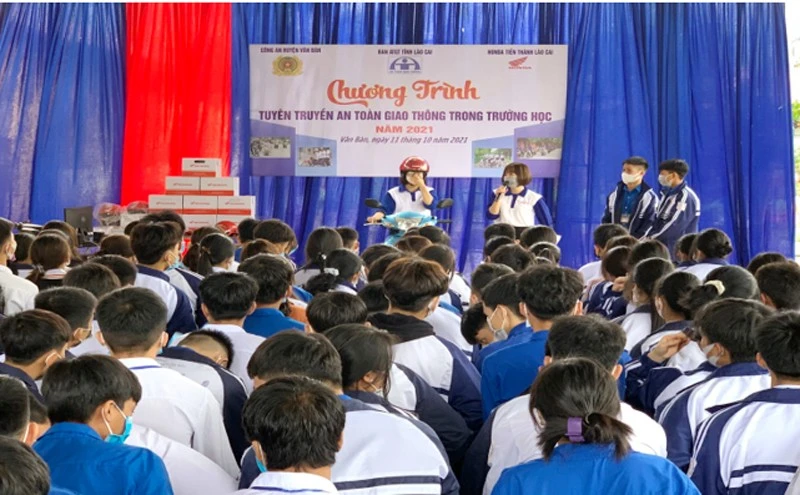 Các tuyên truyền viên hướng dẫn học sinh đội mũ bảo hiểm đúng cách khi tham gia giao thông.