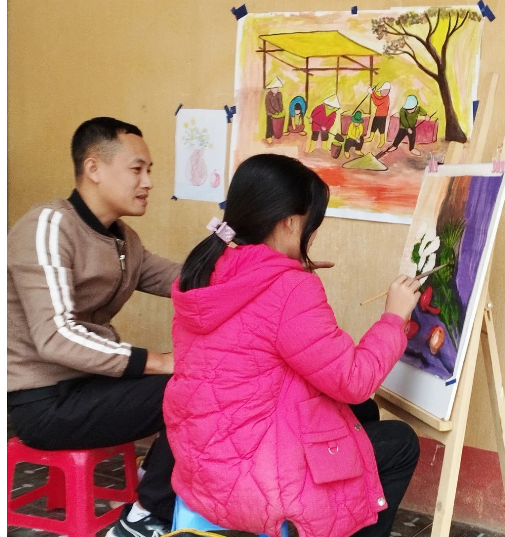 Thầy giáo Nguyễn Thanh Tùng, giáo viên Mỹ thuật Trường Phổ thông Dân tộc bán trú Tiểu học và THCS Bản Cái (huyện Bắc Hà) hướng dẫn Lò Thị Chài vẽ.