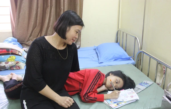 Chị Thanh Hằng ngắm con gái Minh Thư vẽ tranh trên giường bệnh.