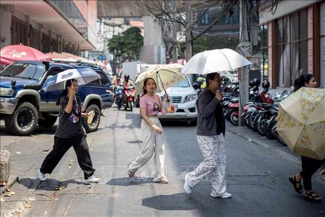 Người dân dùng ô che nắng khi di chuyển trên phố ở Bangkok, Thái Lan. Ảnh tư liệu: AFP/TTXVN