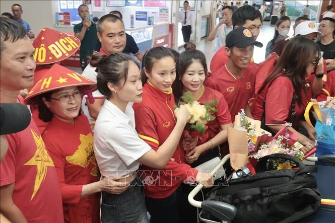 Các cầu thủ đội tuyển nữ Việt Nam trong vòng vây của người hâm mộ tại sân bay quốc tế Nội Bài.