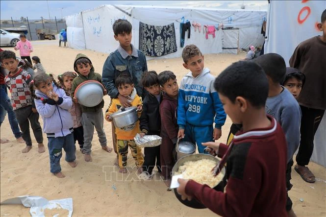 Trẻ em nhận thức ăn cứu trợ tại thành phố Rafah, Dải Gaza ngày 18/3/2024. Ảnh: THX/TTXVN