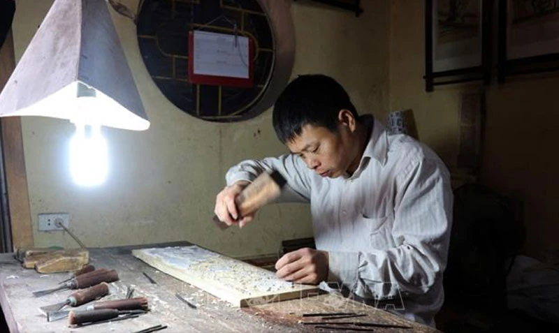 Người làm tranh dân gian Đông Hồ đục ván khắc gỗ để in tranh.