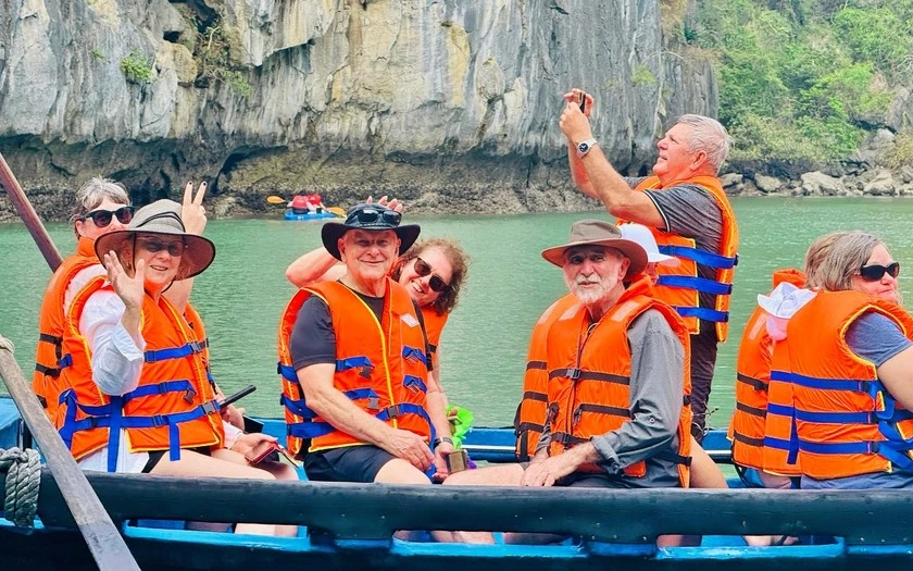 Khách quốc tế trải nghiệm khám phá vịnh Hạ Long bằng loại thuyền truyền thống trong tour du lịch Việt Nam.