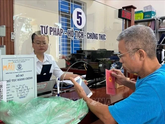 Cán bộ xã Chuyên Mỹ (Hà Nội) hỗ trợ người cao tuổi hoàn thiện thủ tục hành chính.
